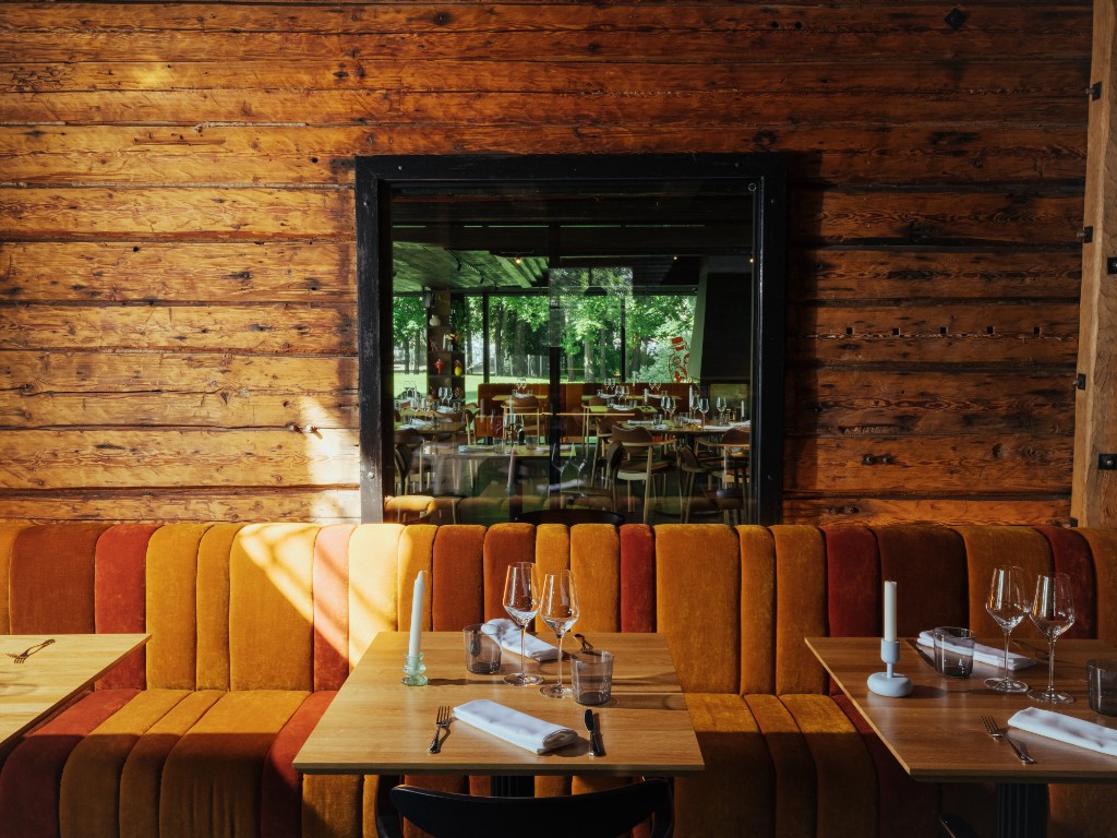 The Rogue Rouge dining room — log wall, banquette and set tables